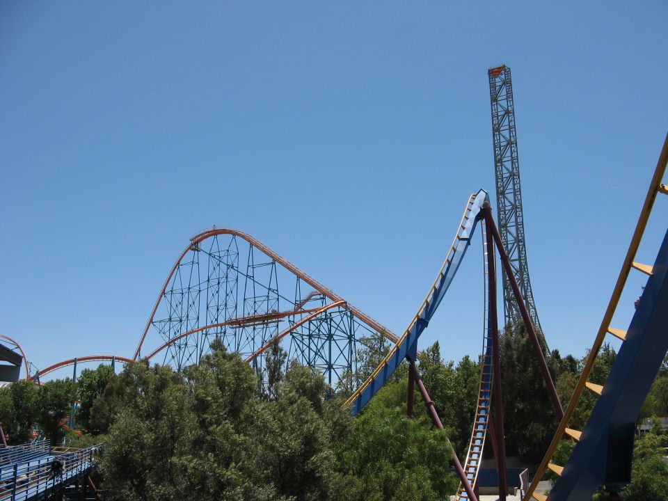 Orange, blue and maroon roller coaster tracks against clear blue sky