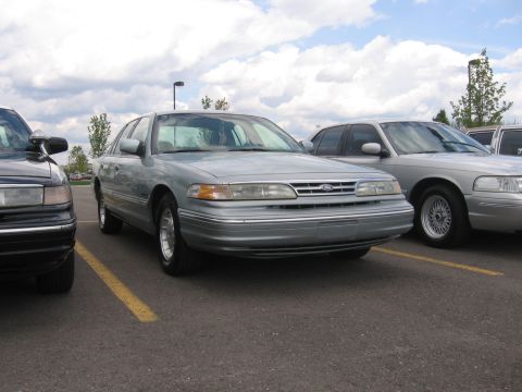1988 Mercury Grand Marquis - Two full-size sedans, likely Ford Crown Victoria and Mercury Grand Marquis models, parked in a lot.