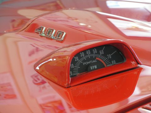 1969 Pontiac Firebird - A Pontiac tachometer is mounted on the hood of a red car, with a "400" badge visible nearby.