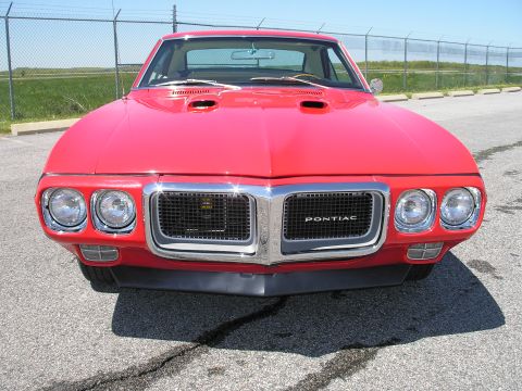 1969 Pontiac Firebird - Frontal view of a red 1969 Pontiac Firebird, showing its distinctive grille and hood scoops.