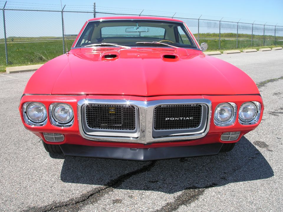 Red 1969 Pontiac Firebird front view with dual hood scoops and chrome grille