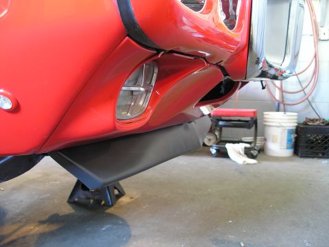 1969 Pontiac Firebird - The underside of a red vehicle's front end is supported by jack stands in a garage setting.
