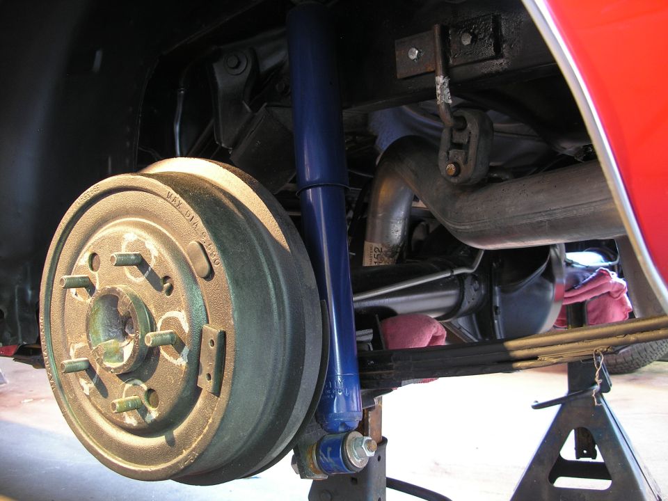 Rear drum brake assembly with blue shock absorber and exhaust pipe