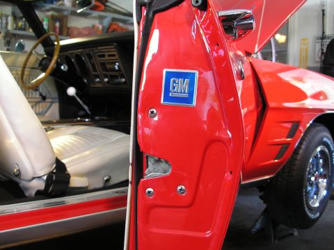 1969 Pontiac Firebird - Interior view of a 1969 Pontiac Firebird, showing white bucket seats and the GM badge on the door jamb.