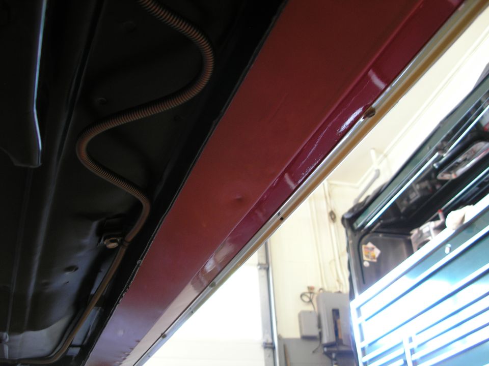 Underside of a vehicle with red painted panel and conduit.