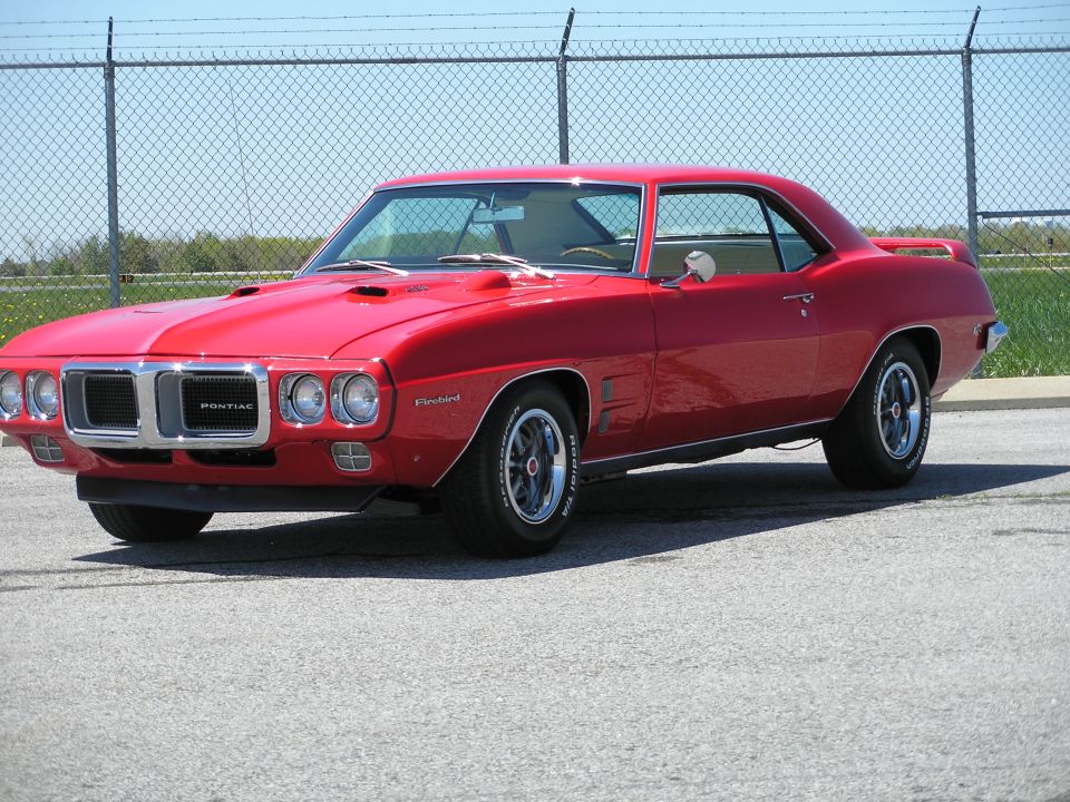 Red 1969 Pontiac Firebird coupe parked outdoors, viewed from a 3/4 front angle.