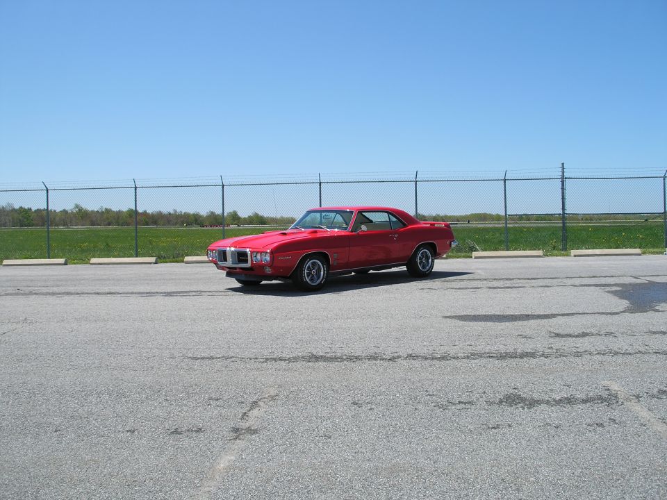 Red 1969 Pontiac Firebird parked in an asphalt lot.