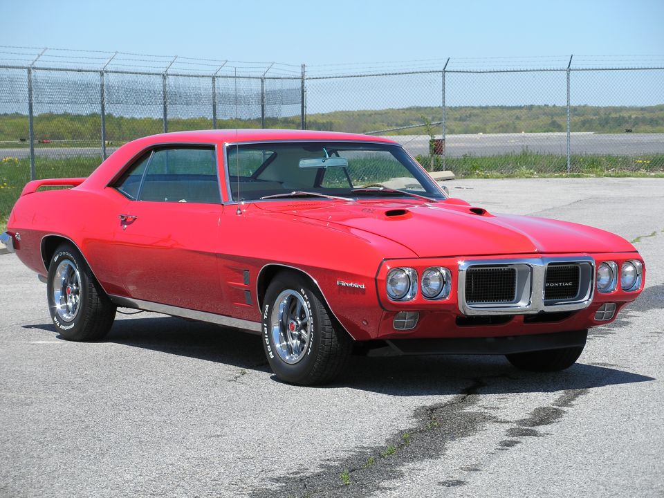 Red 1969 Pontiac Firebird coupe, front three-quarter view on a lot