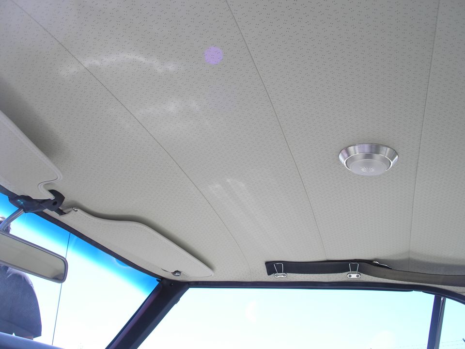 Interior headliner of a vintage car with sun visor and dome light.