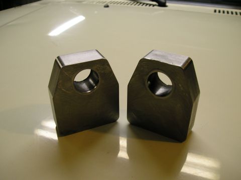 1986 Toyota Hilux - Two metal fabrication tabs with holes are shown on a light-colored surface, possibly a car hood. The tabs have a hexagonal shape with bevel…