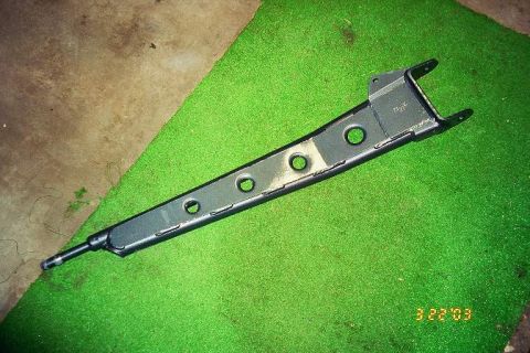 1994 Ford Bronco - A close-up view of a vehicle's suspension part, possibly a control arm, on a green surface.