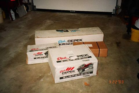 1994 Ford Bronco - Several boxes of Dick Cepek suspension parts are stacked on a garage floor.