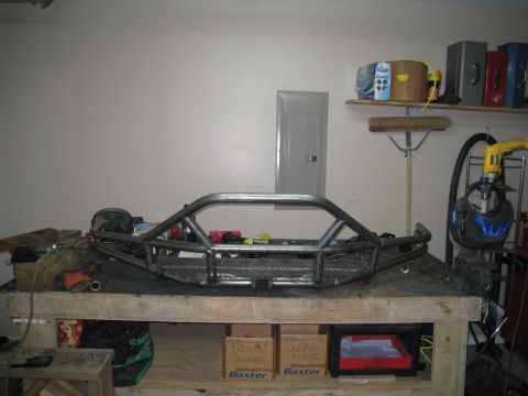 1996 Ford Bronco - A custom metal fabrication, likely a bumper or roll cage, is displayed on a workbench in a garage setting. Various tools and storage boxes…