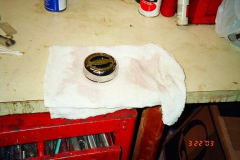 1994 Ford Bronco - A chrome hubcap rests on a white towel, placed on a workbench above a red toolbox.