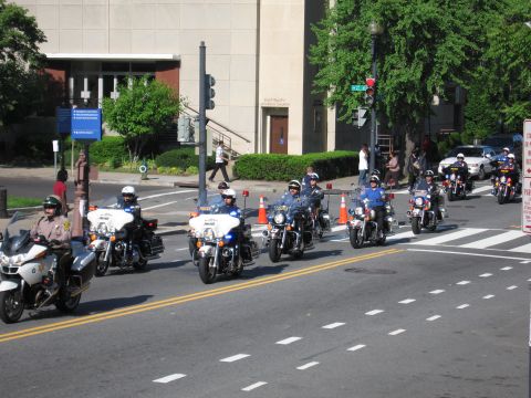 1991 Ford LTD Crown Victoria - group of police motorcycle officers rides toward the camera along a city street with a building behind them.