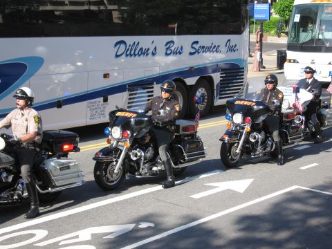 1991 Ford LTD Crown Victoria - Three motorcycle officers sit on their bikes along a street in front of a Dillon's Bus Service motorcoach.
