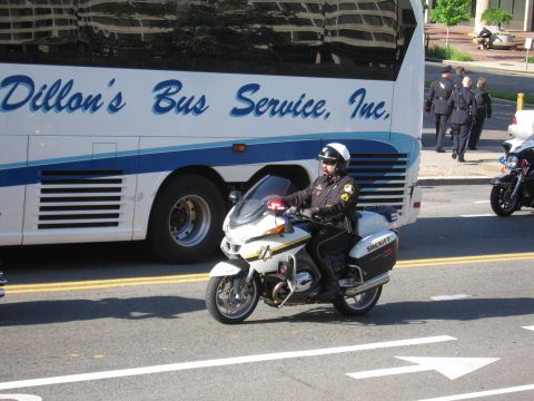 1991 Ford LTD Crown Victoria - sheriff's deputy on a white BMW police motorcycle stops in the street beside a Dillon's Bus Service coach with officers walking nearby.