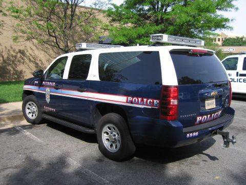 1991 Ford LTD Crown Victoria - blue Chevrolet Suburban marked Fairfax County POLICE 5986 is parked in a lot, shown from the rear three-quarter angle.