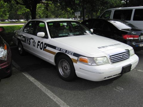 1991 Ford LTD Crown Victoria - white Ford Crown Victoria marked NYS FOP New York State sits in a parking lot beside other vehicles.