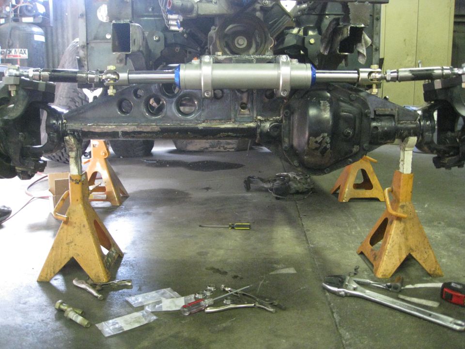 Vehicle front axle assembly on jack stands with steering stabilizer.