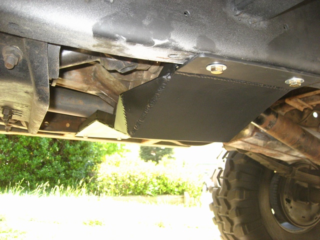 Black steel skid plate bolted under a vehicle frame, off-road tire at right