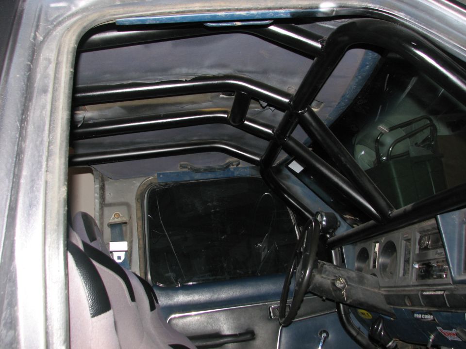 Interior of a vehicle with a black roll cage and racing seat.