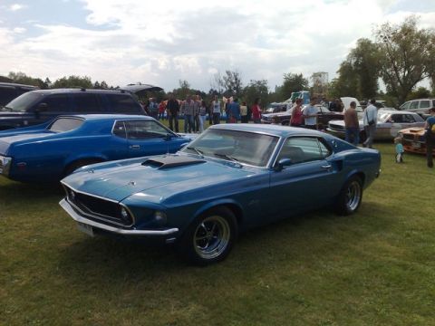 1991 Ford Crown Victoria - A blue classic coupe is displayed at an outdoor event with other vehicles and people in the background.