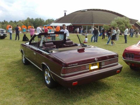 1991 Ford Crown Victoria - A maroon convertible is parked on grass with people and a building in the background.
