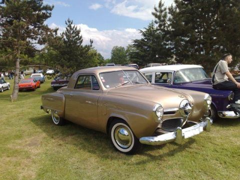 1991 Ford Crown Victoria - A gold coupe with classic chrome details sits on a grassy field at a car show.