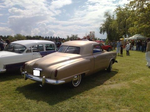 1991 Ford Crown Victoria - A gold coupe is parked on a grassy field at an outdoor event with other vehicles and people around.