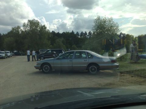 1991 Ford Crown Victoria - Side view of a silver sedan parked in an outdoor lot on a cloudy day.