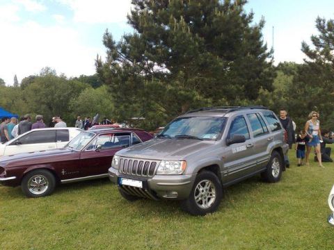 1991 Ford Crown Victoria - Two classic vehicles, a Jeep Grand Cherokee and a Ford Mustang, are displayed on a grassy field.