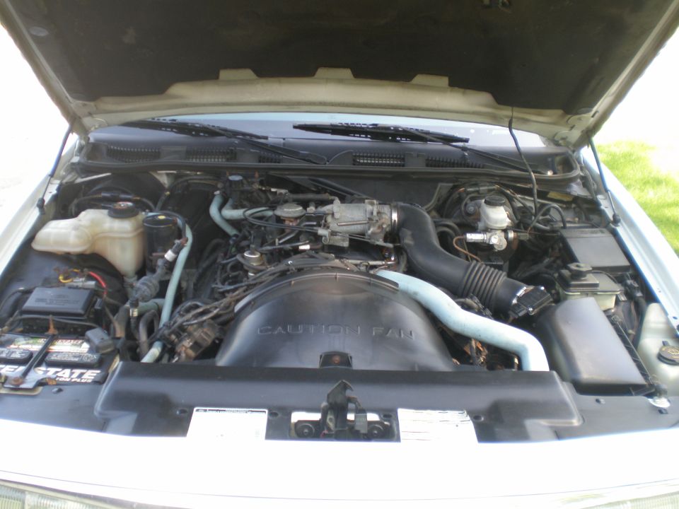 Engine bay with "CAUTION FAN" shroud and blue hoses