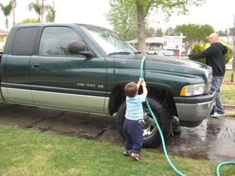 1991 Ford Crown Victoria - Father and son wash a green Dodge Ram pickup truck in the driveway.