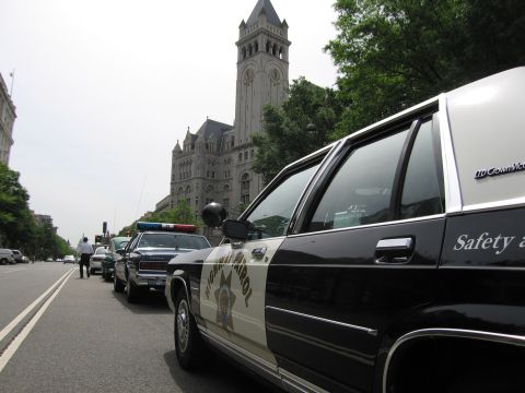 1991 Ford LTD Crown Victoria - Close side view of a black-and-white Highway Patrol Ford Crown Victoria cruiser parked on a street with the clock-tower Old Post Office bui…