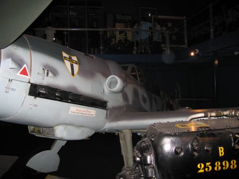 1991 Ford LTD Crown Victoria - Side view of a gray fighter aircraft fuselage with shield emblem, displayed above an aircraft engine marked B 25898.