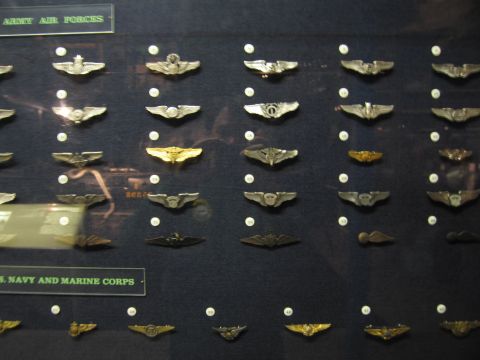 1991 Ford LTD Crown Victoria - glass museum case displaying rows of military aviator wing badges labeled Army Air Forces and Navy and Marine Corps.