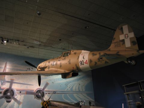 1991 Ford LTD Crown Victoria - tan desert-camouflage fighter aircraft marked C.202 and 90-4 with white tail cross suspended over a mural in a museum hall.