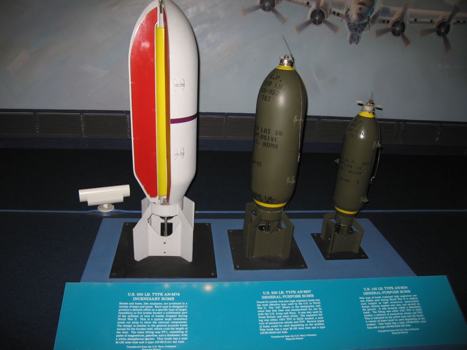 Three WWII aerial bombs of differing sizes displayed on stands with placards