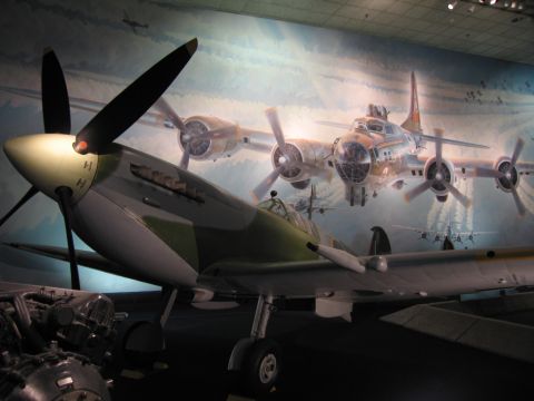 1991 Ford LTD Crown Victoria - green-and-silver WWII fighter aircraft displayed in front of a large mural depicting a four-engine B-17-style bomber in flight.