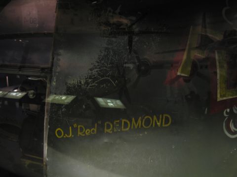 1991 Ford LTD Crown Victoria - dark aircraft fuselage panel painted with yellow cursive crew-name lettering reading O.J. "Red" REDMOND.