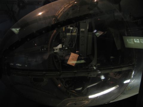 1991 Ford LTD Crown Victoria - clear glazed nose dome of a WWII aircraft, enclosing internal framework and instruments, viewed in a dim museum.