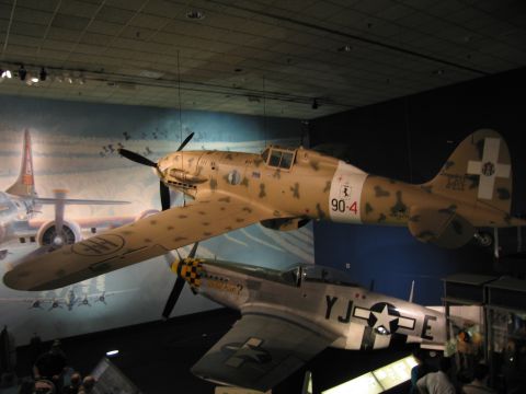 1991 Ford LTD Crown Victoria - tan-camouflaged WWII fighter coded 90-4 with cross markings, suspended above a US fighter marked 'YJ-E' with a star insignia.