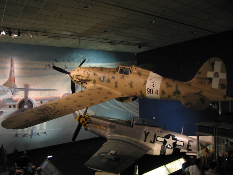 Tan-camouflage WWII fighter coded 90-4 above a star-marked US fighter