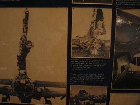 1991 Ford LTD Crown Victoria - Framed wartime photographs in a museum exhibit show severe combat damage to a WWII bomber's tail and rear fuselage.
