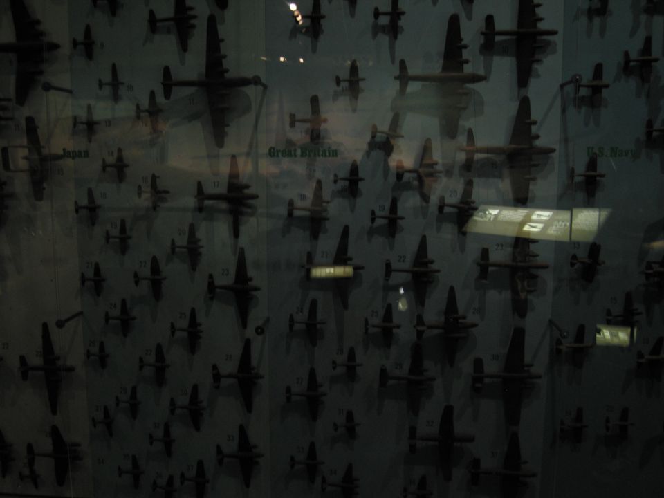 Backlit panel of small aircraft silhouette models labeled by nation behind glass