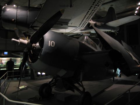 1991 Ford LTD Crown Victoria - nose and propeller of a dark twin-engine military aircraft numbered 10 fill the frame inside a museum hangar.