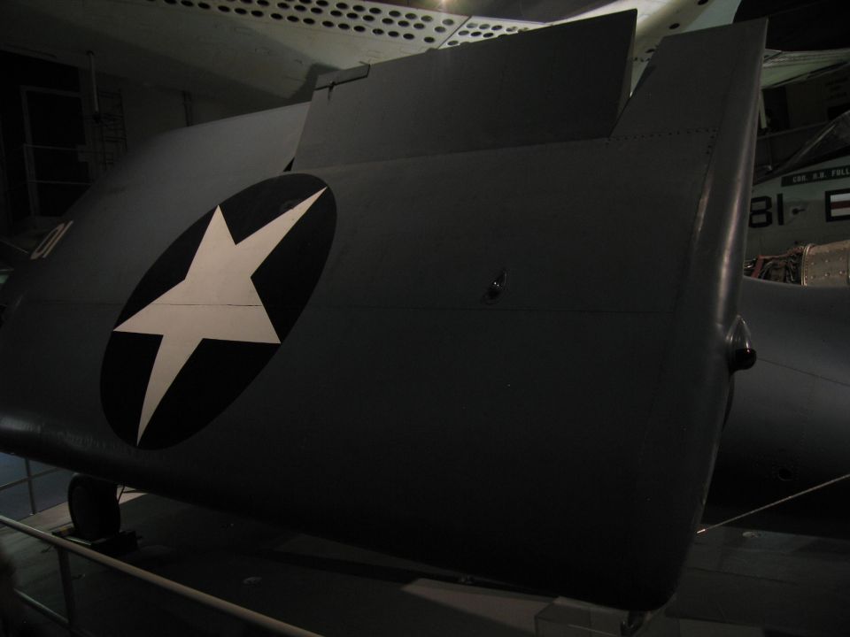 Folded gray aircraft wing with a white star-in-circle national insignia in a museum