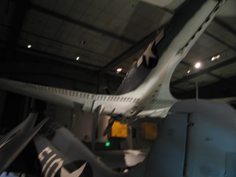 1991 Ford LTD Crown Victoria - blurred low-angle shot captures the underside and tails of military aircraft suspended in a museum hangar.