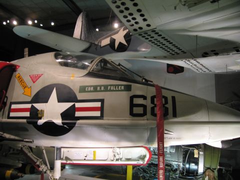 1991 Ford LTD Crown Victoria - gray Navy attack jet numbered 681 with star insignia and CDR R.B. Fuller marking is suspended in a museum.